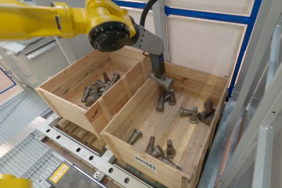 Dévracage : un robot saisit des pièces en vrac dans une caisse en bois.