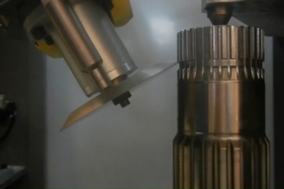 Ébavurage robotisé d’un arbre cannelé en acier : l’outil au contact des cannelures.